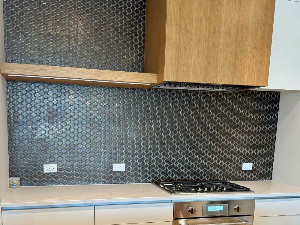black custom backsplash in a kitchen with a wooden vent cover